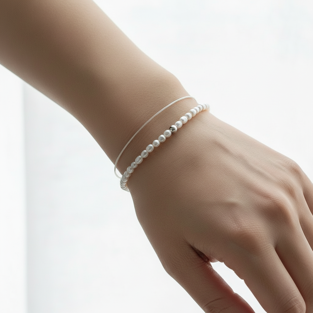 체인 은팔찌와 진주 팔찌를 착용한 여성